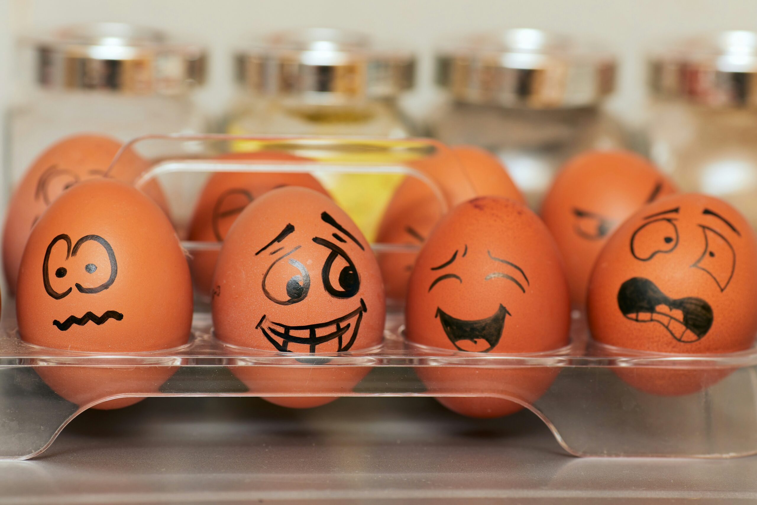 Eggs in a carton have expressive faces drawn on them, showcasing a range of emotions with an impressive touch of emotional intelligence.